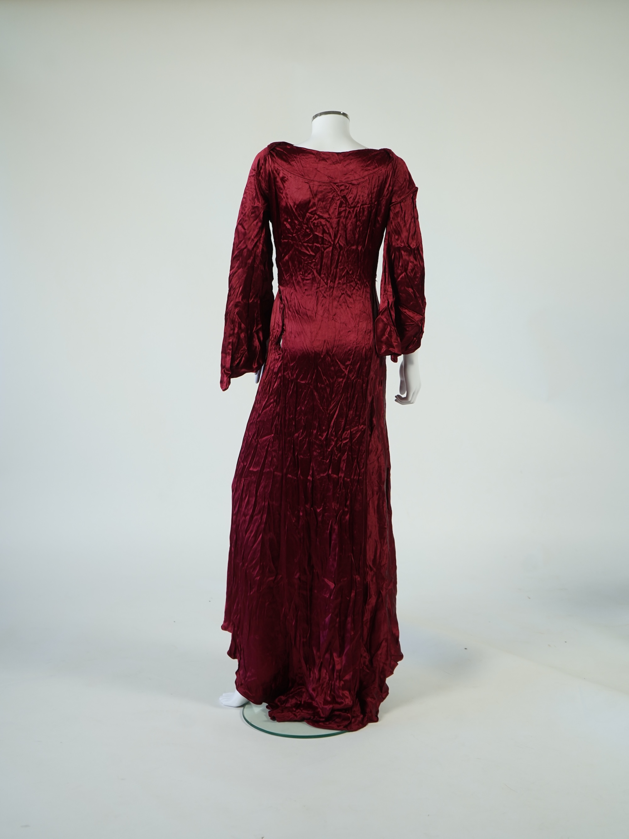 A 1920’s light green silk evening cape with hand batik borders and label: Tito de Canival Mode, together with a navy ladies two piece suit and a maroon satin evening dress. Cape 100cm long. Condition - cape good, navy tw